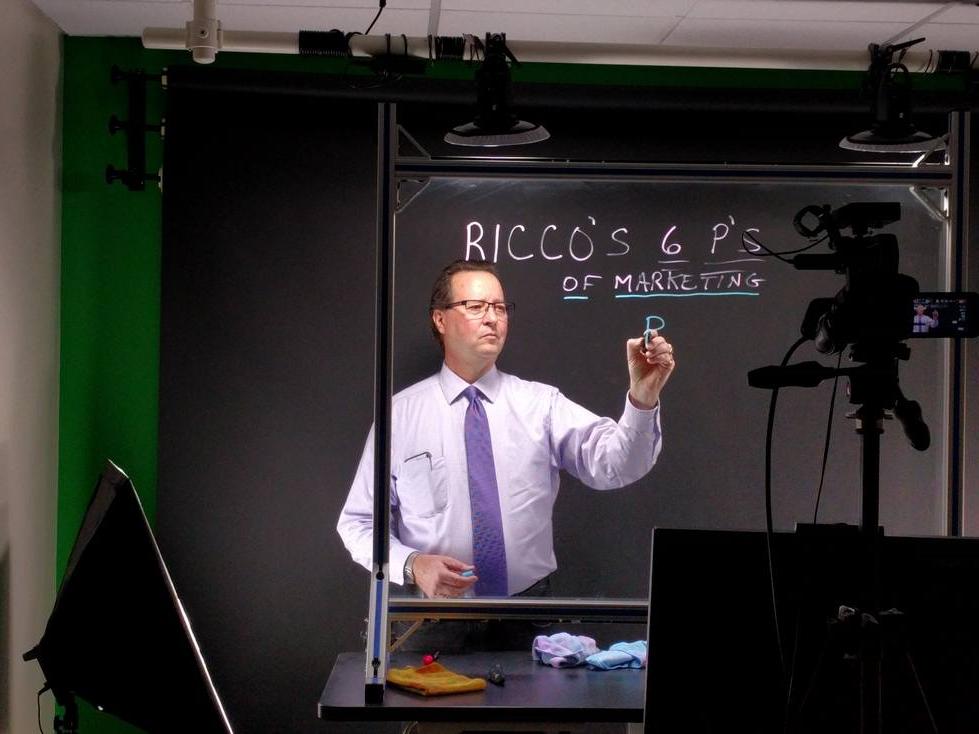 Professor using lightboard with camera filming them